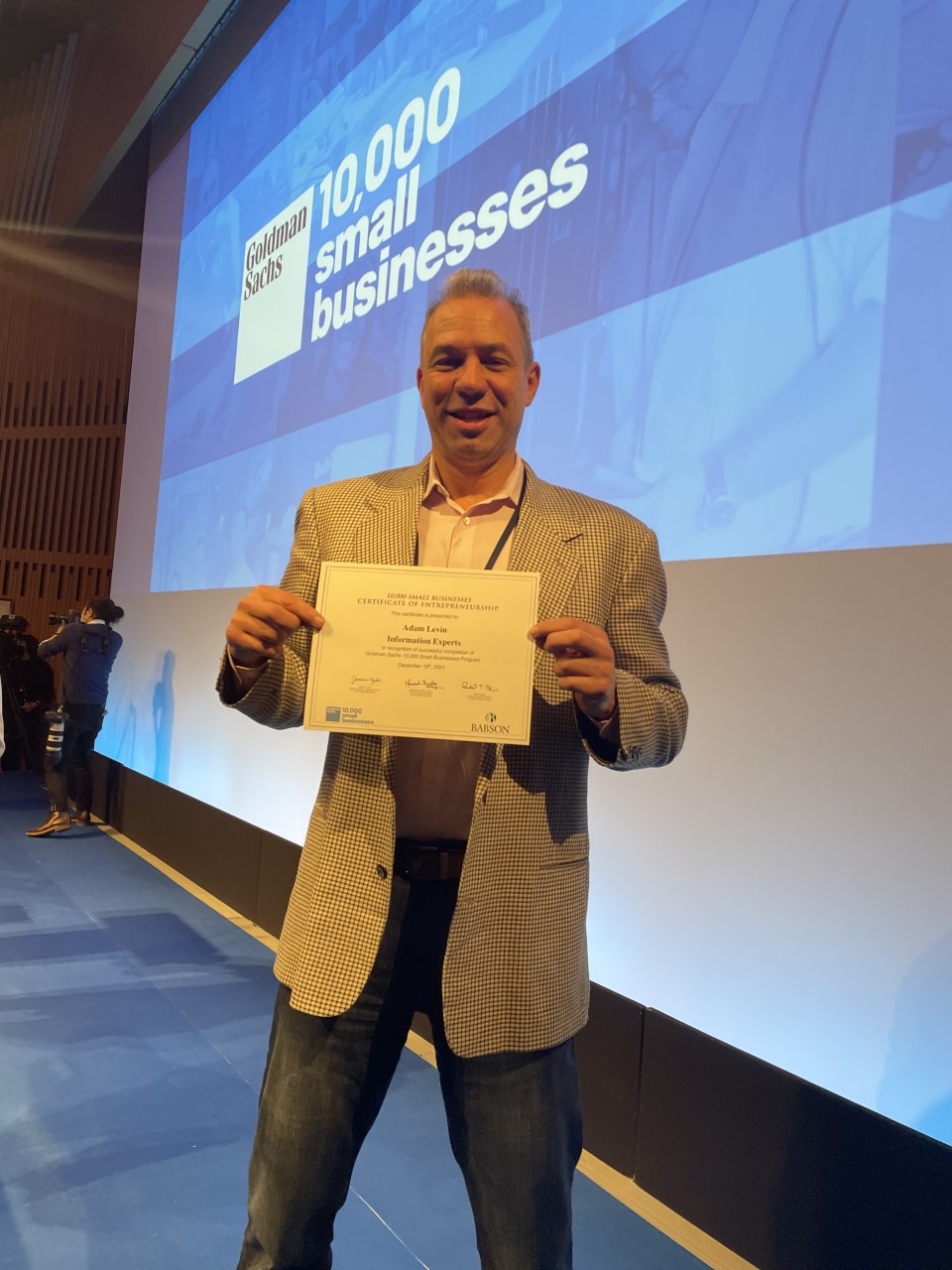Adam holding his Goldman Sachs 10,000 Small Businesses certificate on stage
